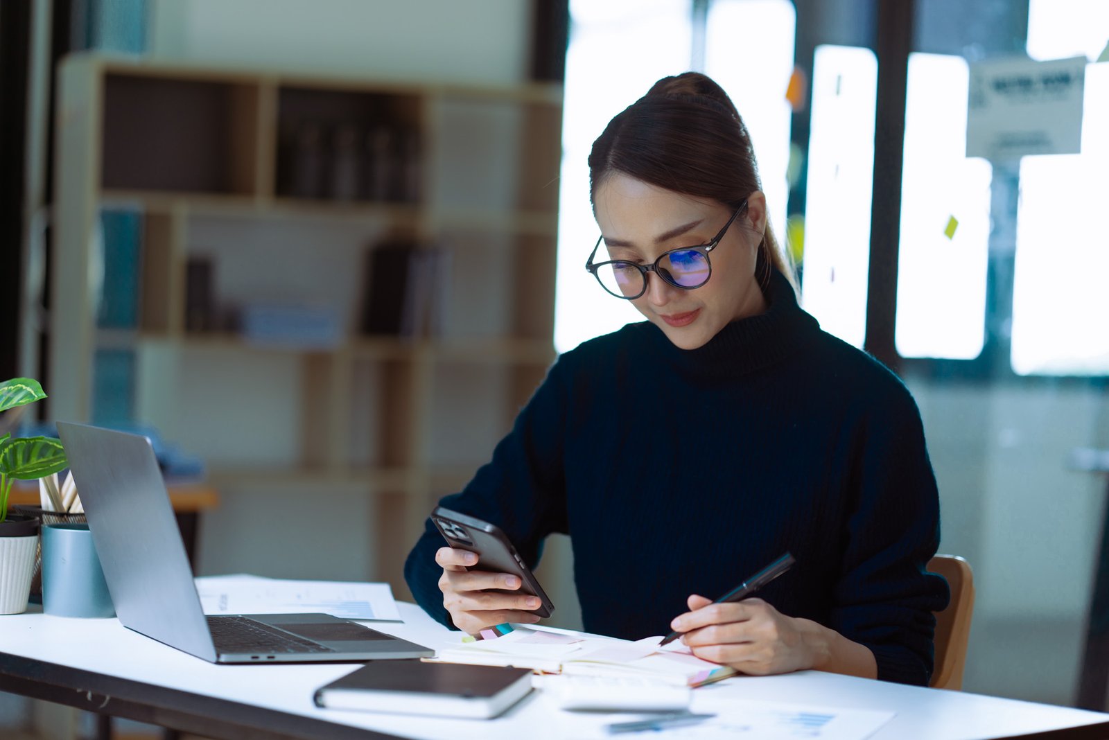 Businesswoman smile got good news on smartphone while working on computer