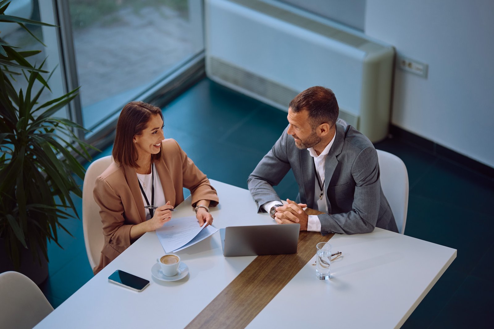 High angle view of happy entrepreneur and her colleague talking during business meeting in the office. Copy space.